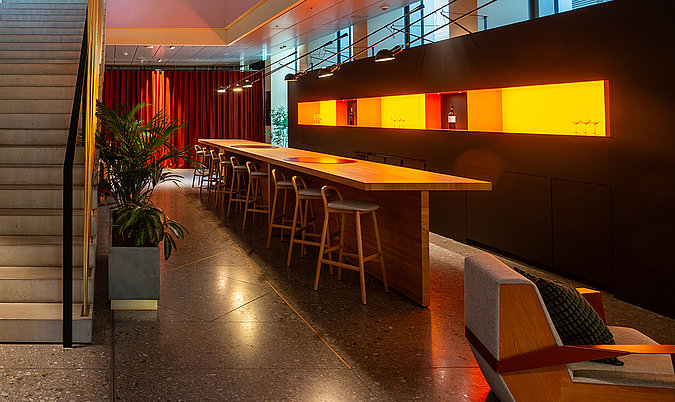 Langer Bartresen mit Barhockern, warmer Beleuchtung und modernem Interiordesign.
