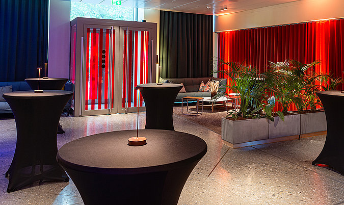 Offener Empfangs- und Networking-Bereich mit Stehtischen, Lounge-Möbeln und stimmungsvoller Beleuchtung.